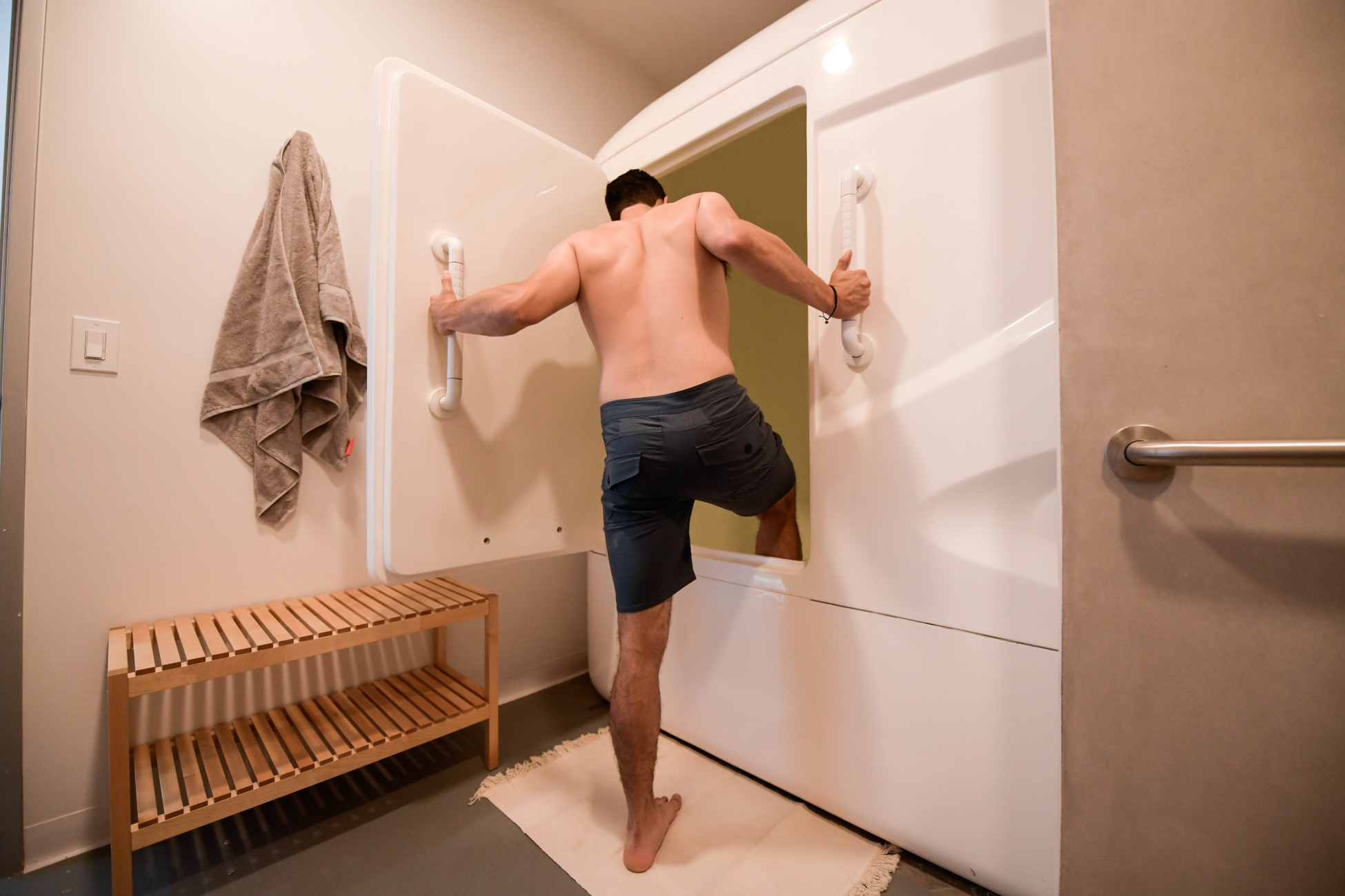 Man at float spa stepping into big float tank